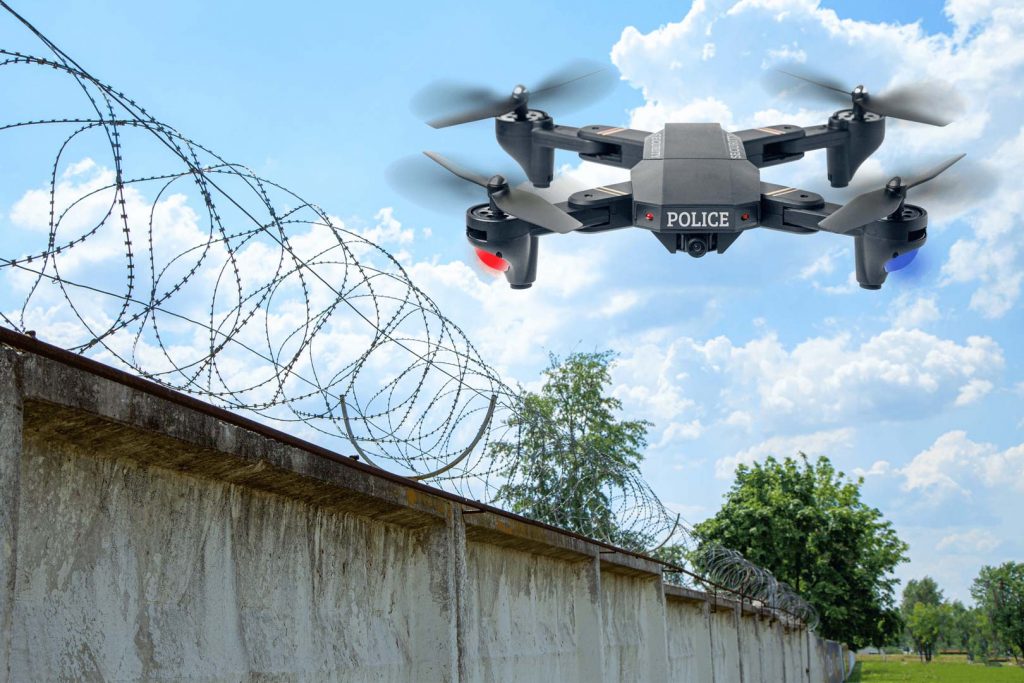 Police drone patrols the area across the sky guarding the wall with barbed wire drone