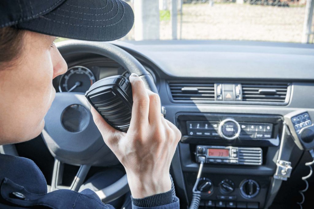 Radio microphone or walkie-talkie in the hand of a policewoman in her patrol car